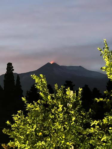 a mountain in the distance with a fire on top at Virdamuri - Etna Country Resort in Giarre