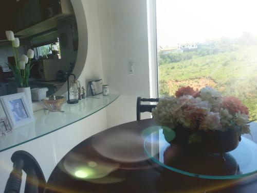 Pousada Flor de Lis Homestay في فولتا ريدوندا: طاولة زجاجية عليها إناء من الزهور