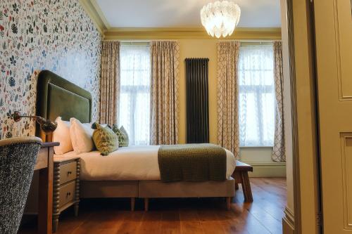 a bedroom with a bed and curtains and a chandelier at The Black Lion Pub & Boutique Guesthouse in London