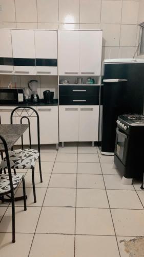 a kitchen with white cabinets and a black refrigerator at Apê da VAN acomoda até 7 pessoas in Garanhuns