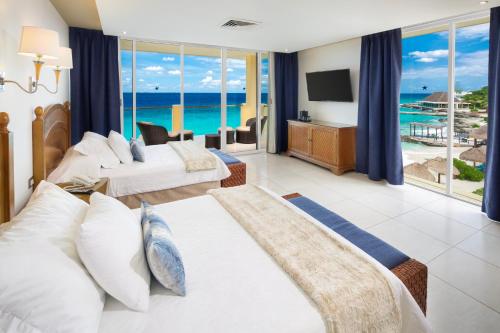 een slaapkamer met 2 bedden en uitzicht op de oceaan bij Playa Azul Cozumel in Cozumel