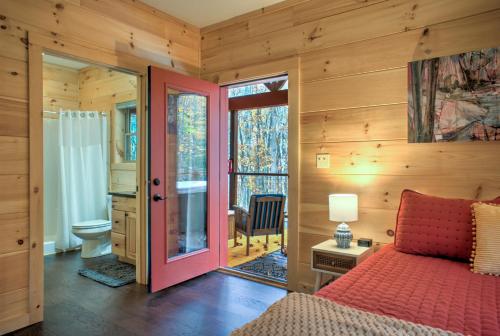 een slaapkamer met een rood bed en een badkamer bij Baby Bear: Peaceful cabin on Bearwallow Mountain with hot tub and close to hiking! in Hendersonville
