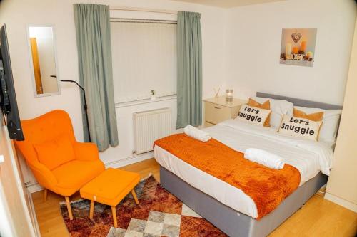 a bedroom with a bed and a orange chair at Charming 2-Bedroom in MANCHESTER in Manchester