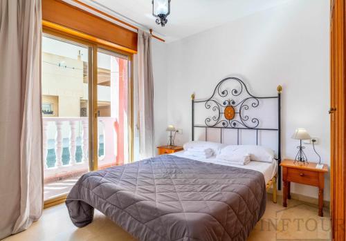 sypialnia z łóżkiem i dużym oknem w obiekcie Inftour Medici Apartamento w mieście Calpe