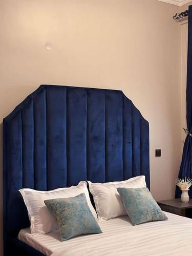 a bed with a blue headboard with two pillows at Cozy apartment in heart of Kampala in Kira