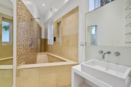 uma casa de banho com uma banheira, um lavatório e um chuveiro em The Mews Apartment In Kensington em Londres