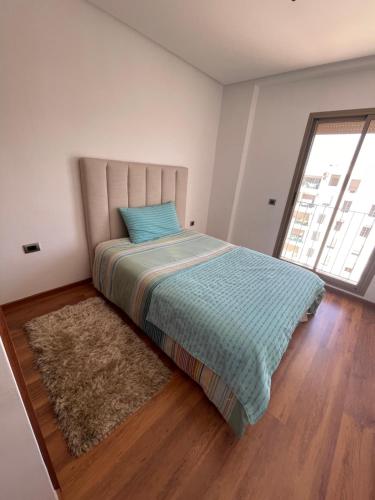 a bedroom with a bed with a blue pillow and a rug at Appartement à louer avec une vue panoramique sur le parc prestigia fes in Fès