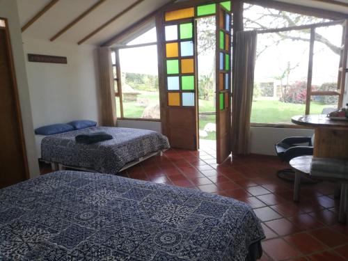 een slaapkamer met 2 bedden en een glas-in-loodraam bij CABAÑA LOS JUANES in Sutamarchán