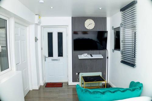曼徹斯特的住宿－Cosy Manchester Haven for Two，客厅配有蓝色的沙发和墙上的时钟