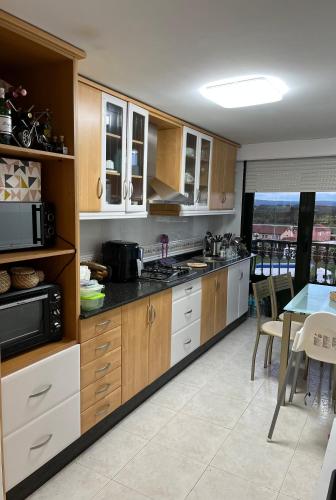 una cocina con armarios de madera y una mesa con comedor. en Apartamento Plaza Melide, en Melide