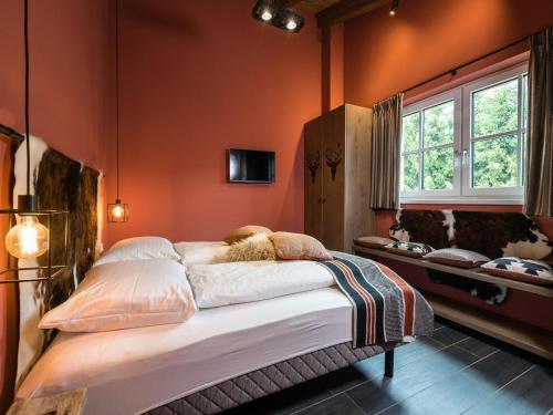a bedroom with a large bed with orange walls at Chalet Schneelöwe XL in Leogang