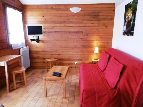 ein Wohnzimmer mit einem roten Sofa und einem Tisch in der Unterkunft Les bruyeres in Brocas