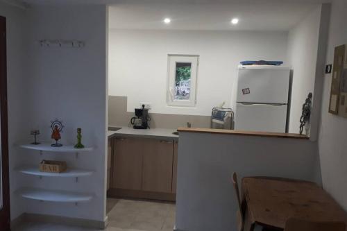 uma cozinha com um frigorífico branco e uma mesa em studio bas de villa, jardin et spa (été seulement) em Le Tignet