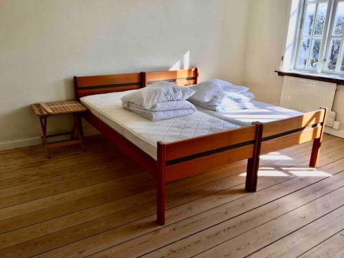 a bed with white sheets and pillows on a wooden floor at Nordsoe Housing-Rørby Kalundborg in Kalundborg