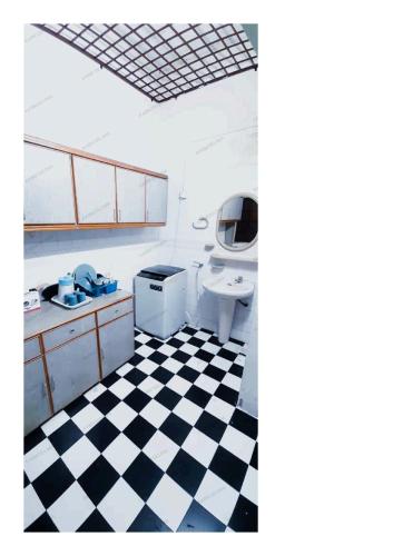 uma casa de banho com piso em xadrez preto e branco em AABM DELIMA HOMESTAY em Ipoh