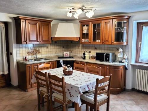 una cocina con mesa y sillas y una cocina con armarios de madera. en Appartamento di montagna LO GROP, en Chambave