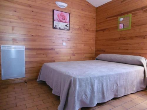 um quarto com uma cama numa parede de madeira em La callune em Brocas