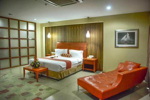 a bedroom with a bed and a couch and a chair at Harbour View Suites in Dar es Salaam