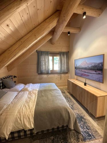 a bedroom with a large bed and a flat screen tv at Chalet NON-SENS by L'Occitane in Hochrindl