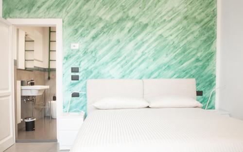 een slaapkamer met een wit bed en een groene muur bij Casa Scotto in Pisa