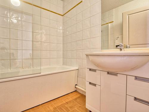 une salle de bain blanche avec un lavabo et une baignoire dans l'établissement Appartement cosy avec piscine, au pied des pistes, parfait pour 4 personnes - FR-1-505-112, à Flumet