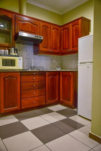 a kitchen with wooden cabinets and a white refrigerator at Harbour View Suites in Dar es Salaam
