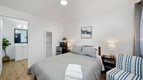 a white bedroom with a bed and a chair at Adventure Lodge in South Lake Tahoe
