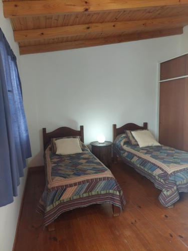 two beds in a room with wooden floors at Departamento en Barrio Los Olmos in Trelew