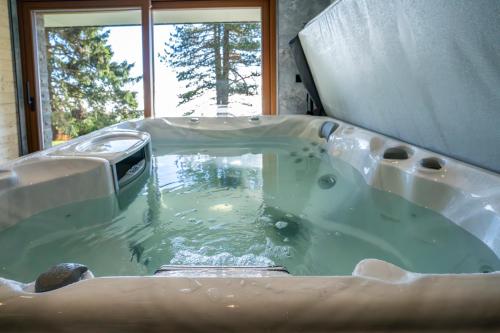 a jacuzzi tub in a room with a window at Chalet NON-SENS by L'Occitane in Hochrindl