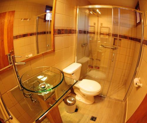 a bathroom with a toilet and a glass shower at Hotel Kimal in San Pedro de Atacama