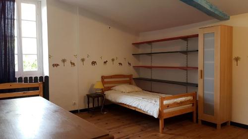 ein Schlafzimmer mit einem Bett, Regalen und einem Tisch in der Unterkunft La masqueria in Montgaillard
