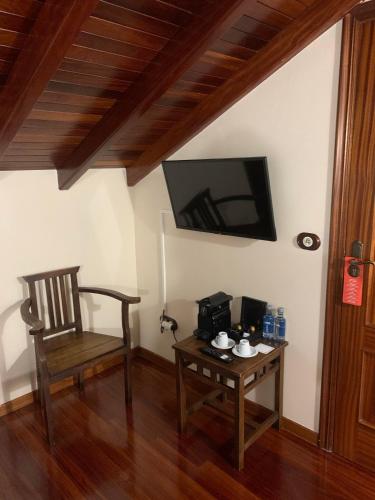 a room with a chair and a table with a tv at Casa de Costoia in Santiago de Compostela