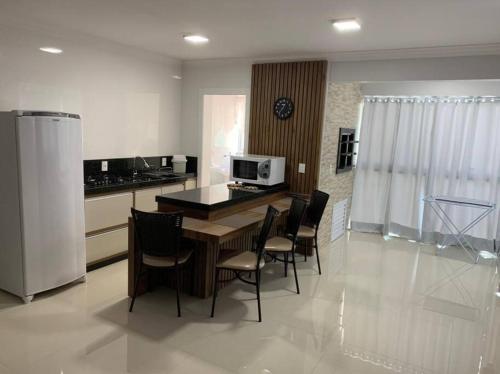 eine Küche mit einem Tisch, Stühlen und einer Mikrowelle in der Unterkunft Lindo Apto NOVO na Avenida, climatizado e aconchegante in Piratuba