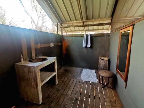 baño con lavabo y suelo de madera en The Tshilli Farm & Lodge, en Maun