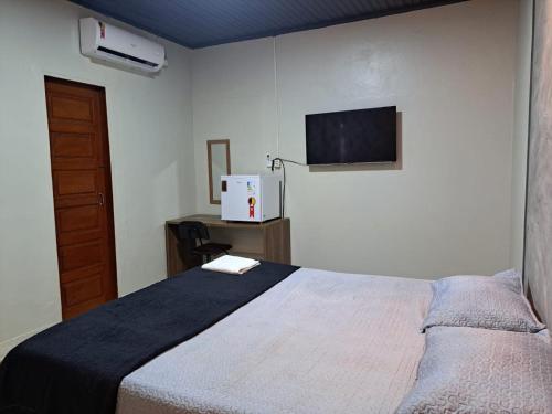 a bedroom with a bed and a flat screen tv at AP 3 - Suíte Confortável e Aconchegante - Pousada Paraíso in Macapá