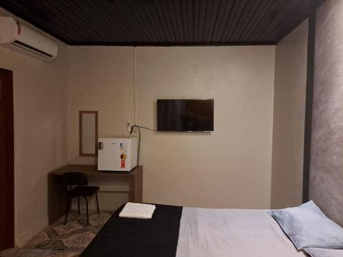 um quarto com uma cama e uma televisão na parede em AP 3 - Suíte Confortável e Aconchegante - Pousada Paraíso em Macapá