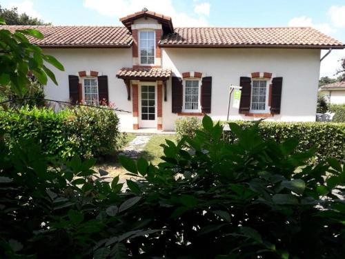 a white house with black shutters and bushes at Lanes in Montgaillard