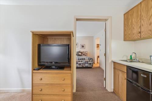 a kitchen with a flat screen tv on a wooden dresser at Deluxe one bedroom suite located on first floor with outdoor heated pool 11517 in Killington