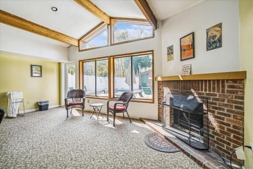a living room with a brick fireplace and windows at Deluxe one bedroom suite located on first floor with outdoor heated pool 11517 in Killington