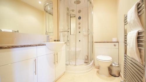 a bathroom with a shower and a toilet and a sink at Crompton Court Apartments in London