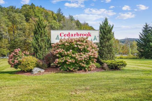 a sign for a car dealership with flowers in a field at Cedarbrook Two Double bed Hotel Room with outdoor heated pool 216 in Killington