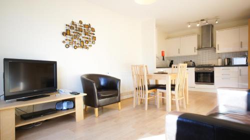 a living room with a television and a table with chairs at Crompton Court Apartments in London