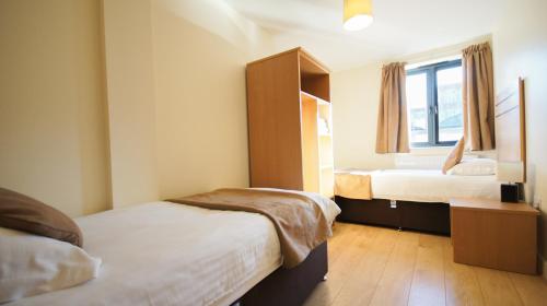 a small bedroom with two beds and a window at Crompton Court Apartments in London