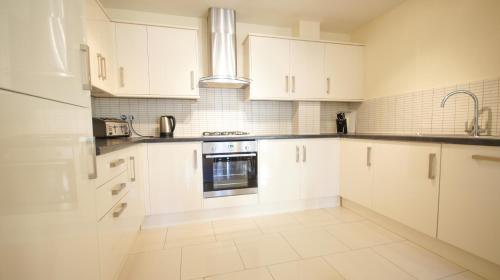 a white kitchen with white cabinets and a sink at Crompton Court Apartments in London