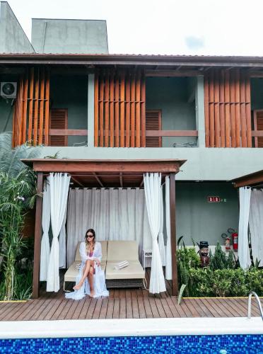 a woman sitting on a bench next to a house at Hiu Hotel in Juquei