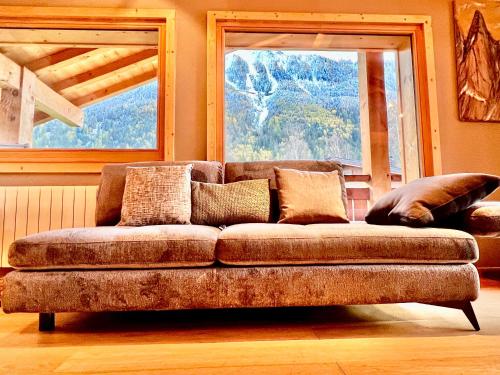 a couch sitting in a living room with two windows at Chalet Isabelle Mountain lodge 5 star 5 bedroom en suite sauna jacuzzi in Chamonix-Mont-Blanc