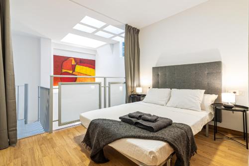 een slaapkamer met een groot wit bed en een schilderij bij Segismundo FreshApartments by Bossh Apartments in Málaga