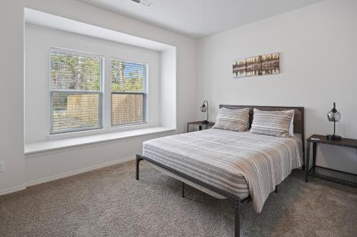 a white bedroom with a bed and two windows at 172 Avocet home in Sunriver