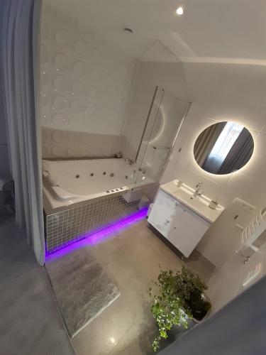 ein Badezimmer mit einer Badewanne und einem Waschbecken mit violetten Lichtern in der Unterkunft Apartamenty "PRZY KATEDRZE" GORZÓW - jacuzzi in Gorzów Wielkopolski