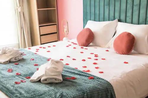 - un lit avec des pétales de rose rouge dans l'établissement Balnéo & Confort, Tram, Parking, à Illkirch-Graffenstaden